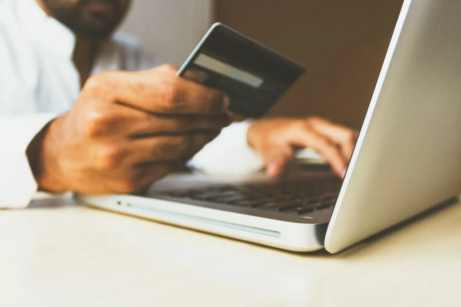 Person paying for an online purchase with a card at their laptop